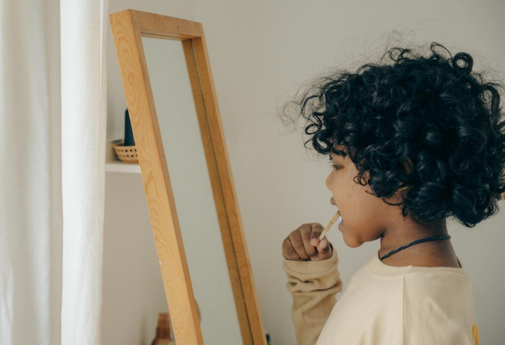 A child brushing their teeth while looking into the mirror.