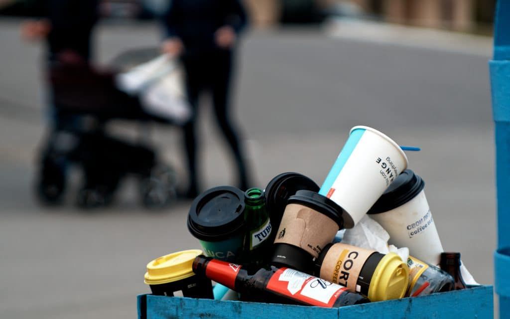 Trash bin full of single use coffee cups.