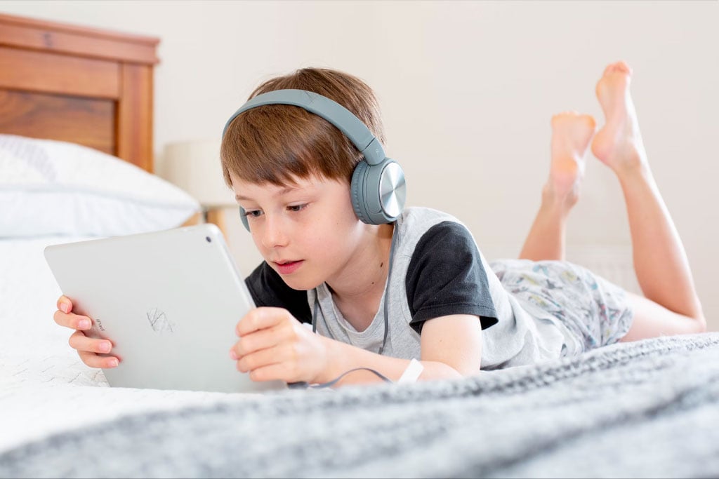 A boy playing with an ipad wearing wireless headphones