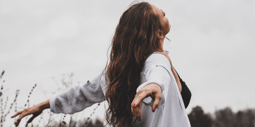 Woman standing in a field with arms wide open